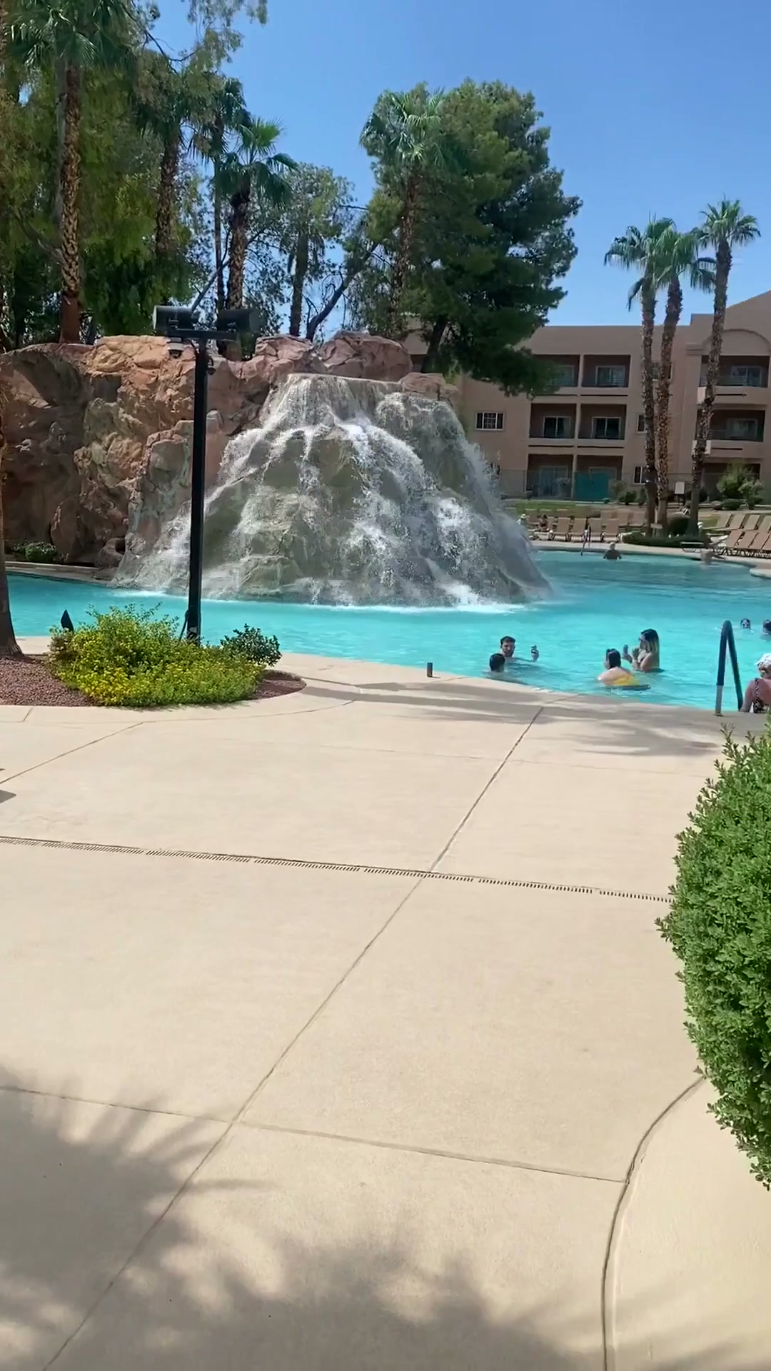 Piscina de CasaBlanca Resort en Mesquite con cascada de roca, palmeras y el hotel al fondo