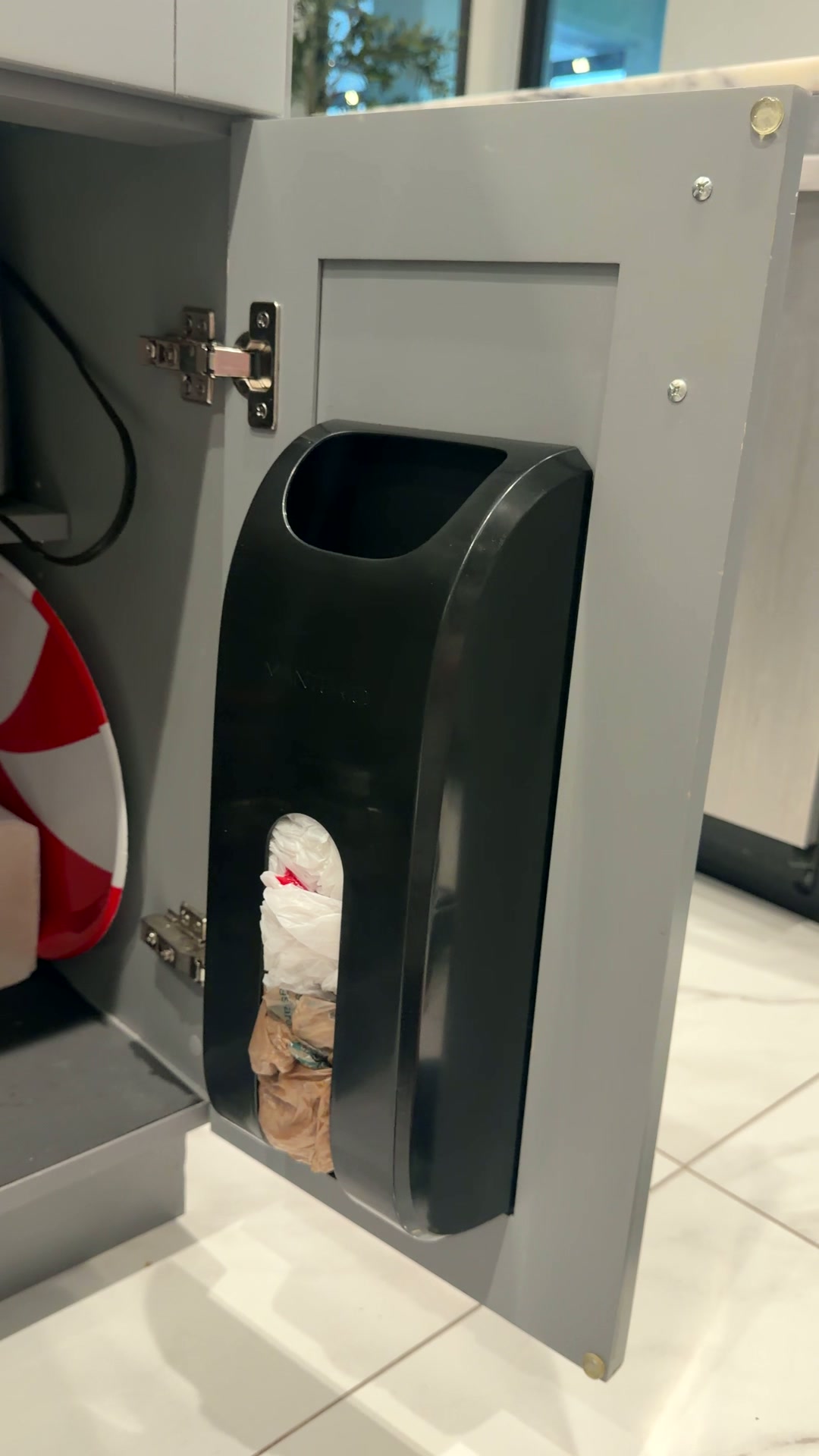 Dispensador negro de bolsas instalado dentro de la puerta de un mueble de cocina