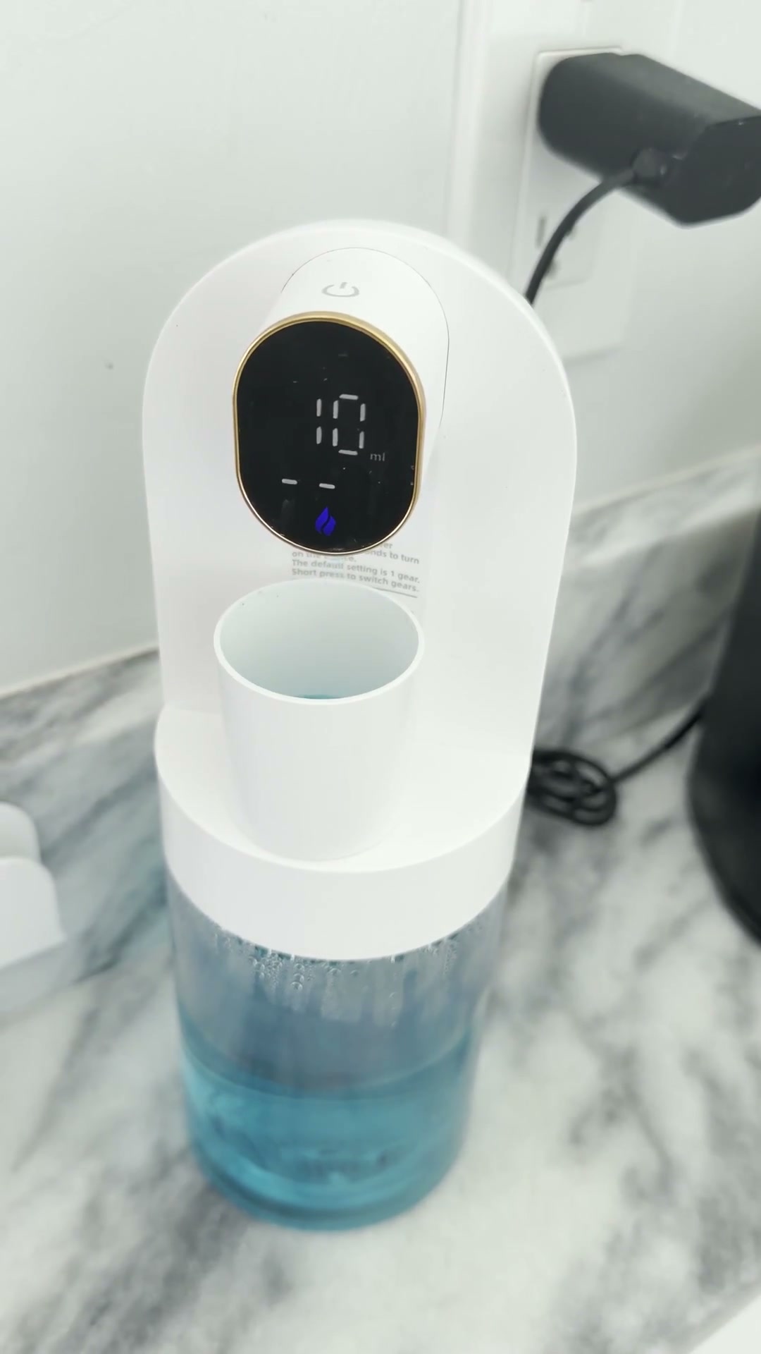 Dispensador de enjuague bucal con un vasito bajo la salida y pantalla digital