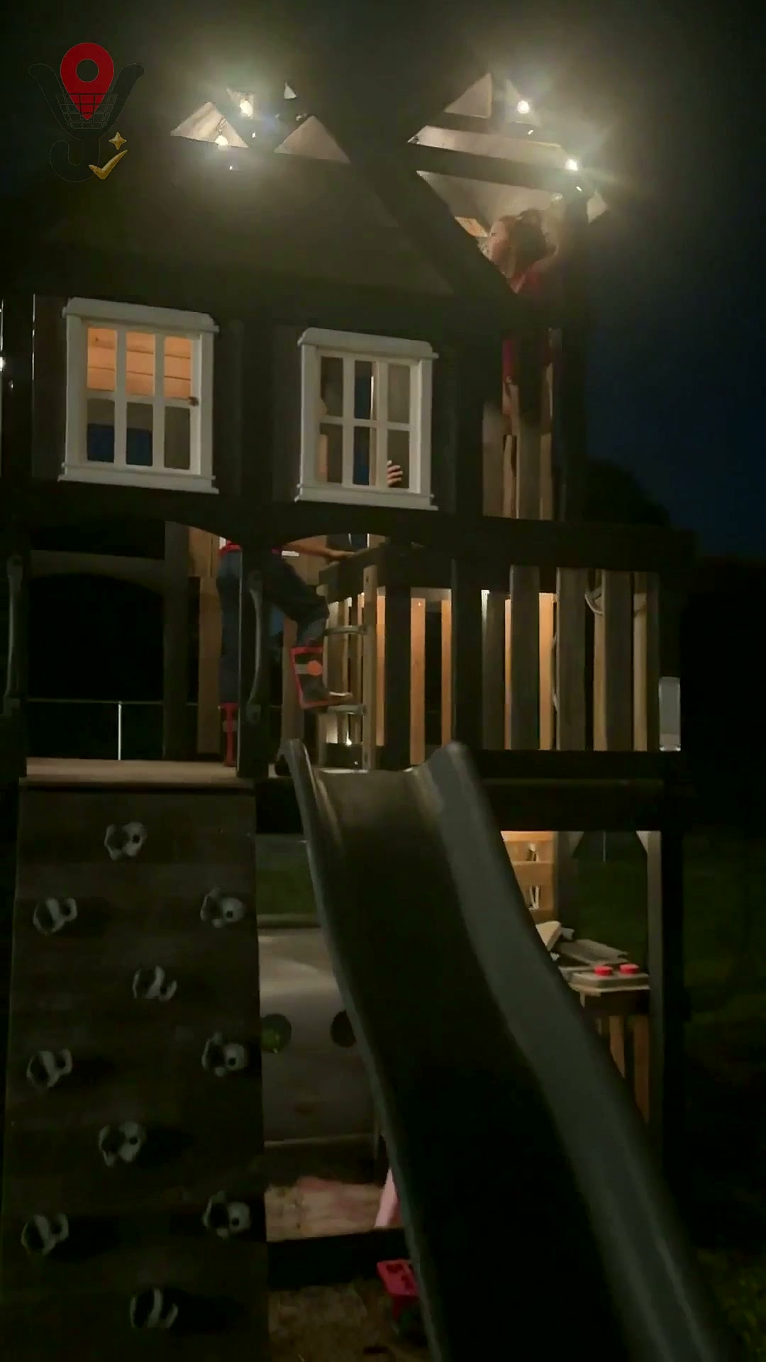 Casita de juegos con tobogán iluminada por una guirnalda solar de noche