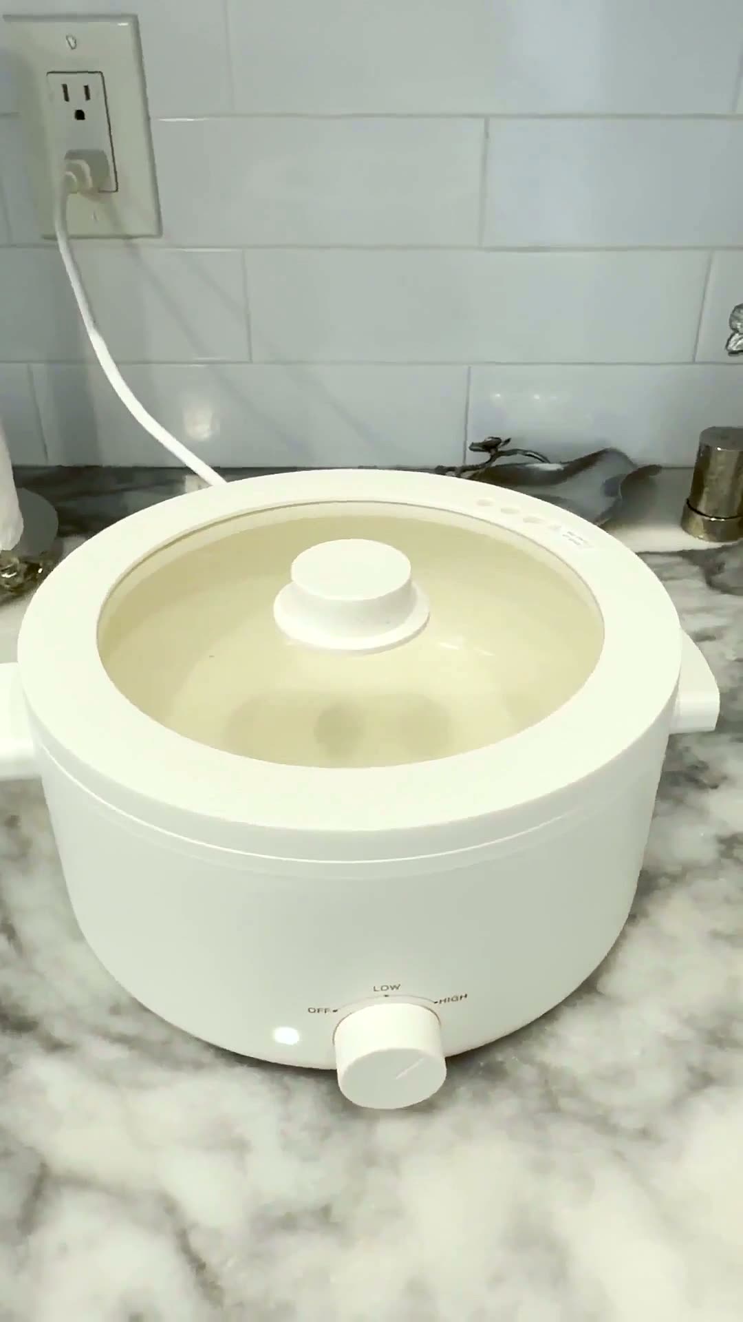 Olla eléctrica blanca con tapa de cristal y mando de temperatura sobre la encimera