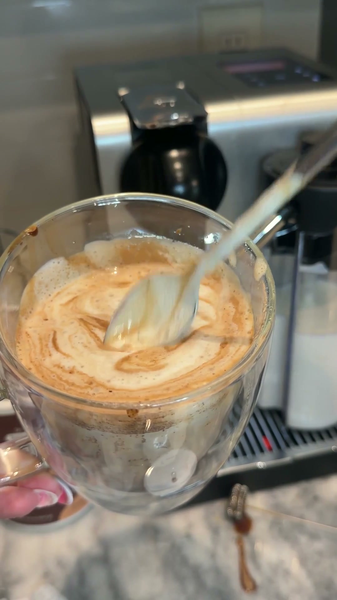 Vaso de Super Café con leche mientras Yane lo remueve con una cuchara
